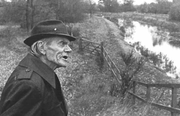 Period black-and-white photograph of the witness Alfred Burtoo, an elderly man in a hat and overcoat, standing on the towpath beside the Basingstoke Canal at Aldershot, near the spot where he said the craft landed on 12 August 1983. This is a real photograph of the actual witness at the real location, not a recreation or illustration.