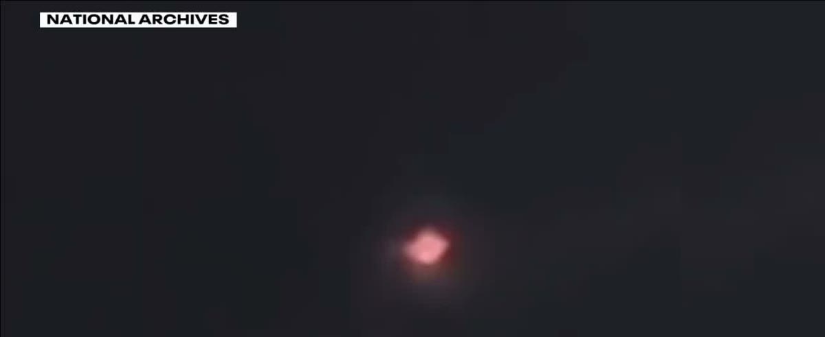 A frame from the footage held in the National Archives Unidentified Anomalous Phenomena Records Collection, shown here within a FOX 9 Minneapolis report. The object is a blurred, glowing point that cycled through colors. One officer filmed it on an iPhone held to a pair of binoculars, which accounts for the soft focus. A brightened crop appears below.