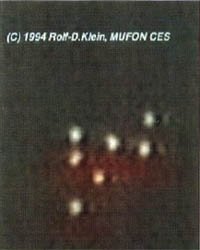 A real video frame of the Greifswald lights, showing a row of luminous spheres with the characteristic reddish glow beneath, the formation that several independent witnesses filmed over the Greifswalder Bodden on the evening of 24 August 1990. This is an actual photographic still from the original 1990 footage, not a recreation or illustration.