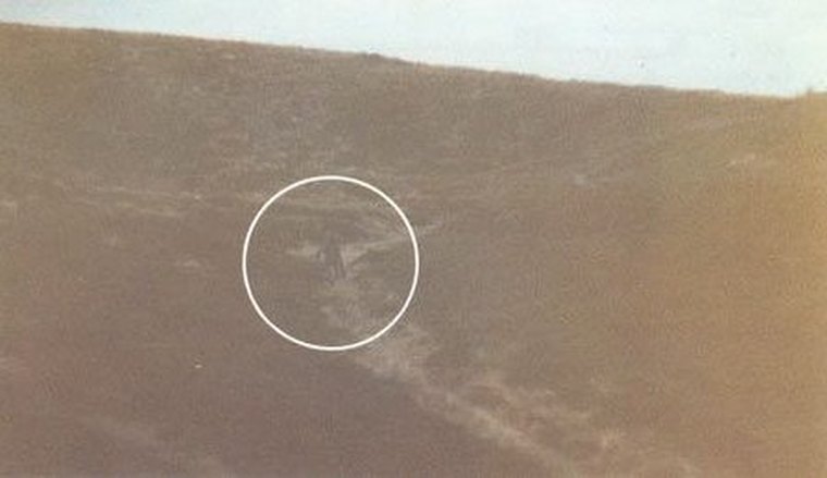 The original grainy colour photograph taken by the witness using the pseudonym Philip Spencer on the morning of 1 December 1987, showing a small dark figure (circled) on the misty slope of Ilkley Moor near White Wells. This is the authentic photograph, not a recreation or render; the Kodak laboratory at Hemel Hempstead found the figure was part of the original untampered negative.