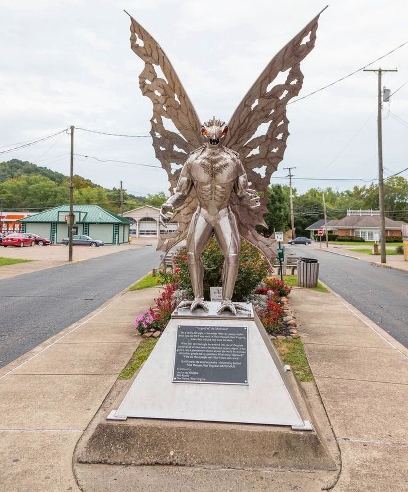The official "Legend of the Mothman" stainless-steel statue and interpretive marker in downtown Point Pleasant, West Virginia. This is a sculptural recreation of the creature, not a photograph of the 1966 entity. The statue was made by sculptor Bob Roach of New Haven, West Virginia, and the marker erected by the town in 2003; its plaque recounts the November 1966 TNT-area encounter by the two young couples.