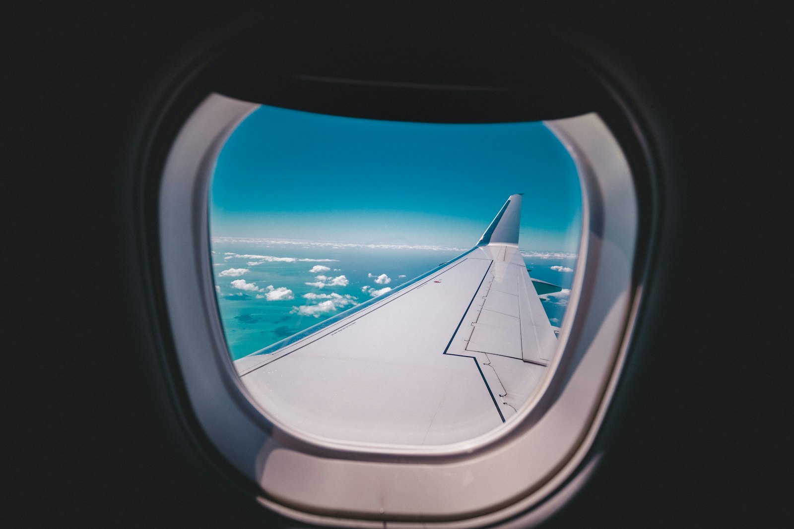 The view a commercial flight crew has of the airspace off the New York coast, where in AARO’s FY2024 reporting window an aircrew reported a near miss with a cylindrical object. No imagery of the object has been released; the sole public record is one line in the Pentagon’s annual UAP report. Shown: an airliner wing over ocean and cloud, illustrative.