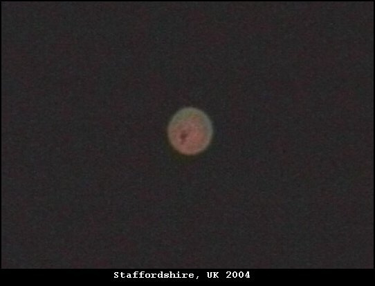 A still frame from video footage said to have been recorded at roughly 2 am on 8 August 2004 at Lichfield, Staffordshire, showing a single bright orange ball of light. This is a video still of the reported object, not a recreation or CGI; the footage has never been released for independent frame-by-frame analysis.
