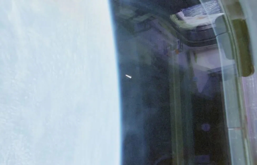 One of the three released STS-80 photographs (NASA-UAP-D030 series), showing the small, whitish triangular object at left against the limb of the Earth, framed by Space Shuttle Columbia's window, 1996.