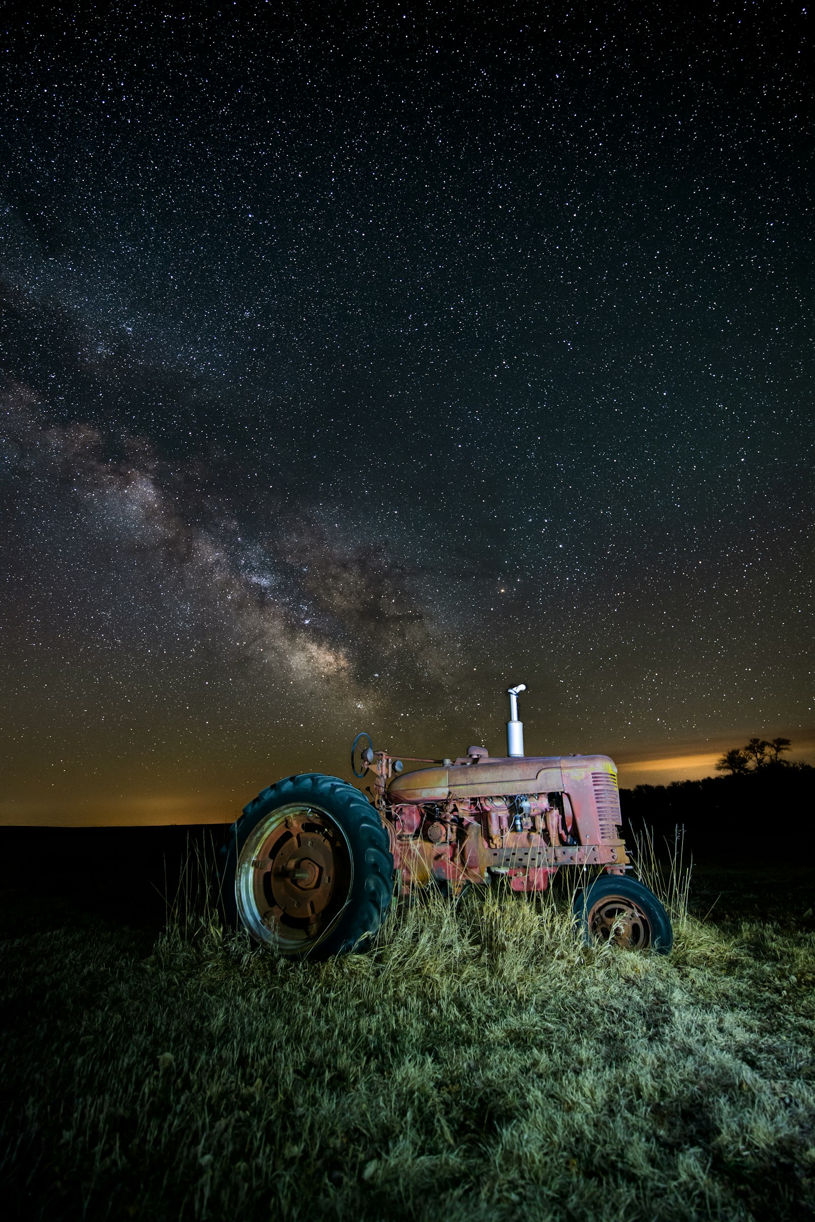 A vintage tractor in a field under the night sky. Antônio Villas Boas was alone on his tractor, ploughing after dark to escape the daytime heat, when the events of the night of 15 to 16 October 1957 began. This is a contextual photograph of the kind of work and setting involved, not an image of the actual sighting; no verified photograph of the object exists, and the only freely licensed portrait labelled with his name is in fact a different man, a Brazilian Supreme Court justice.